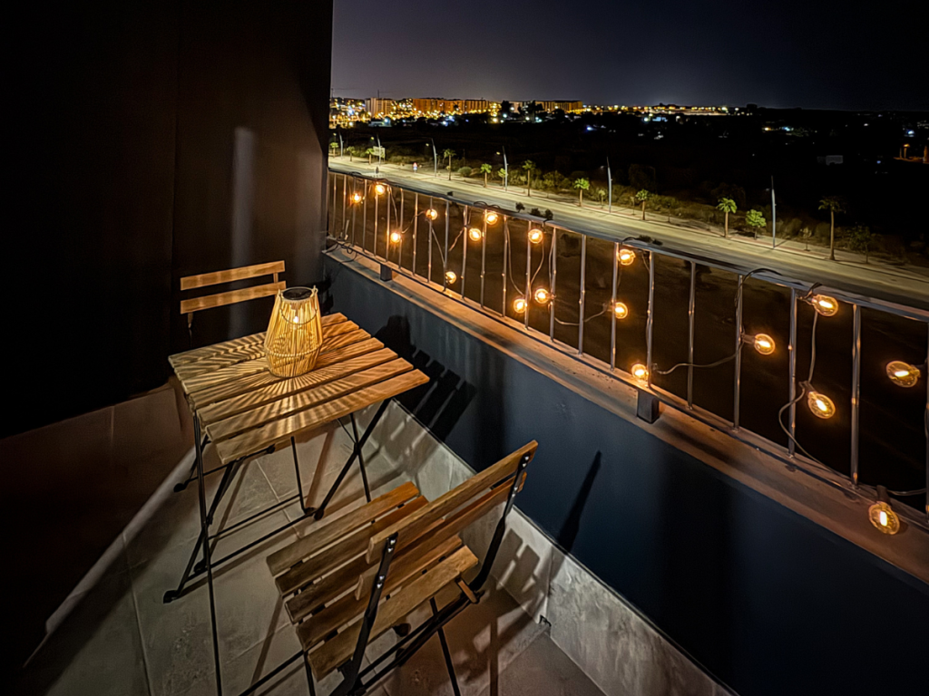 Outdoor fairy lights strung across small balcony on summer evening staycation
