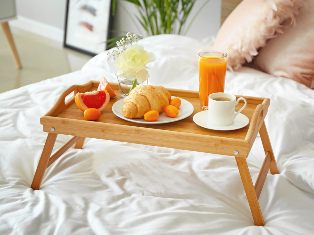 Bamboo breakfast tray with legs holding coffee and pastries for hotel style morning routine at home