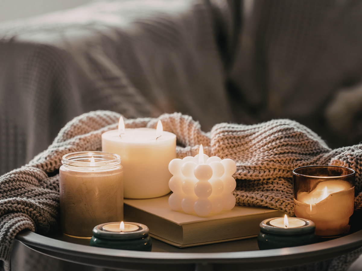Lit soy wax candle on a coffee table in a softly lit newly decorated living room]