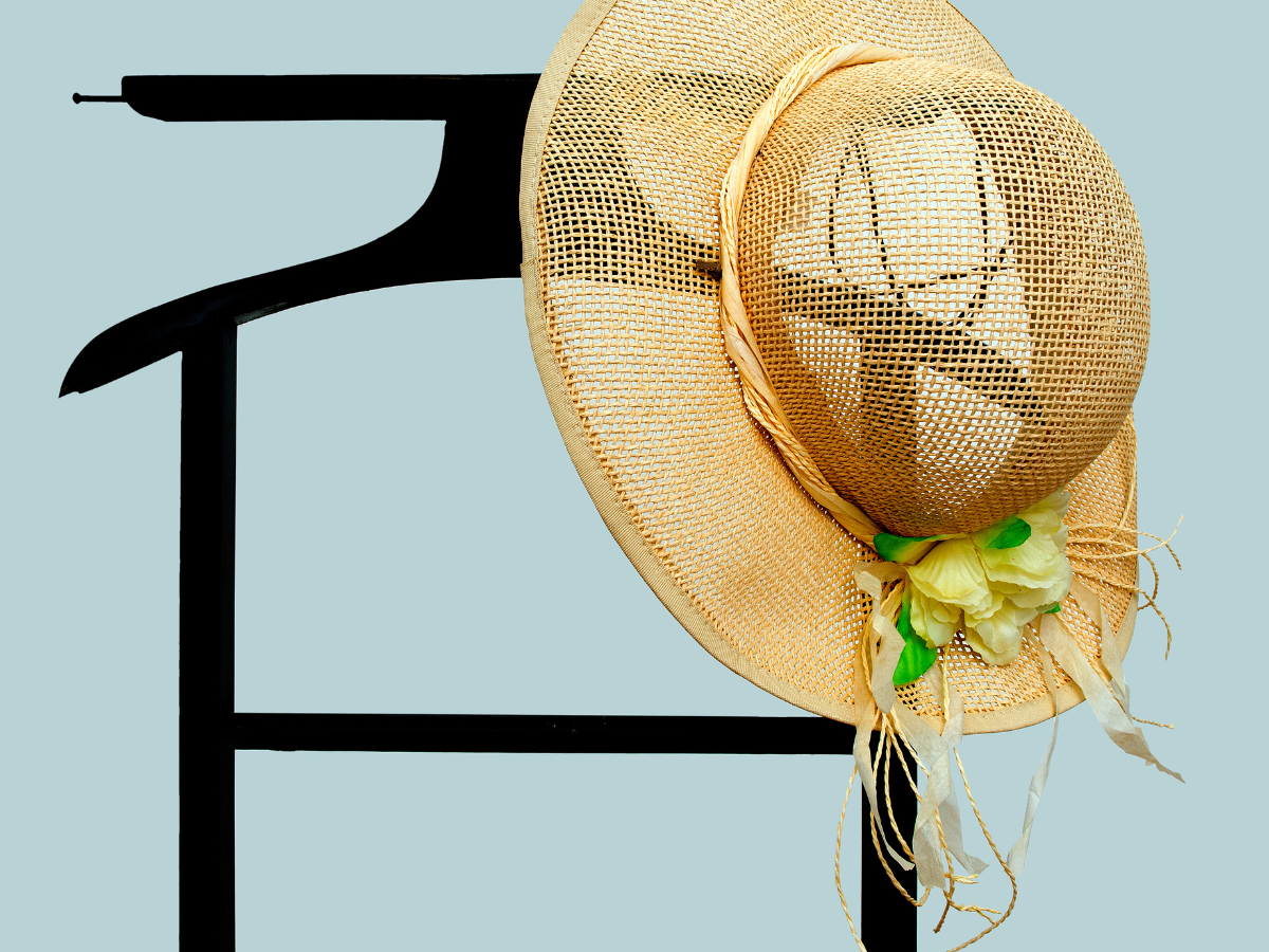 Black valet stand holding summer hat in a tidy organised bedroom – bedroom organisation ideas for adults.