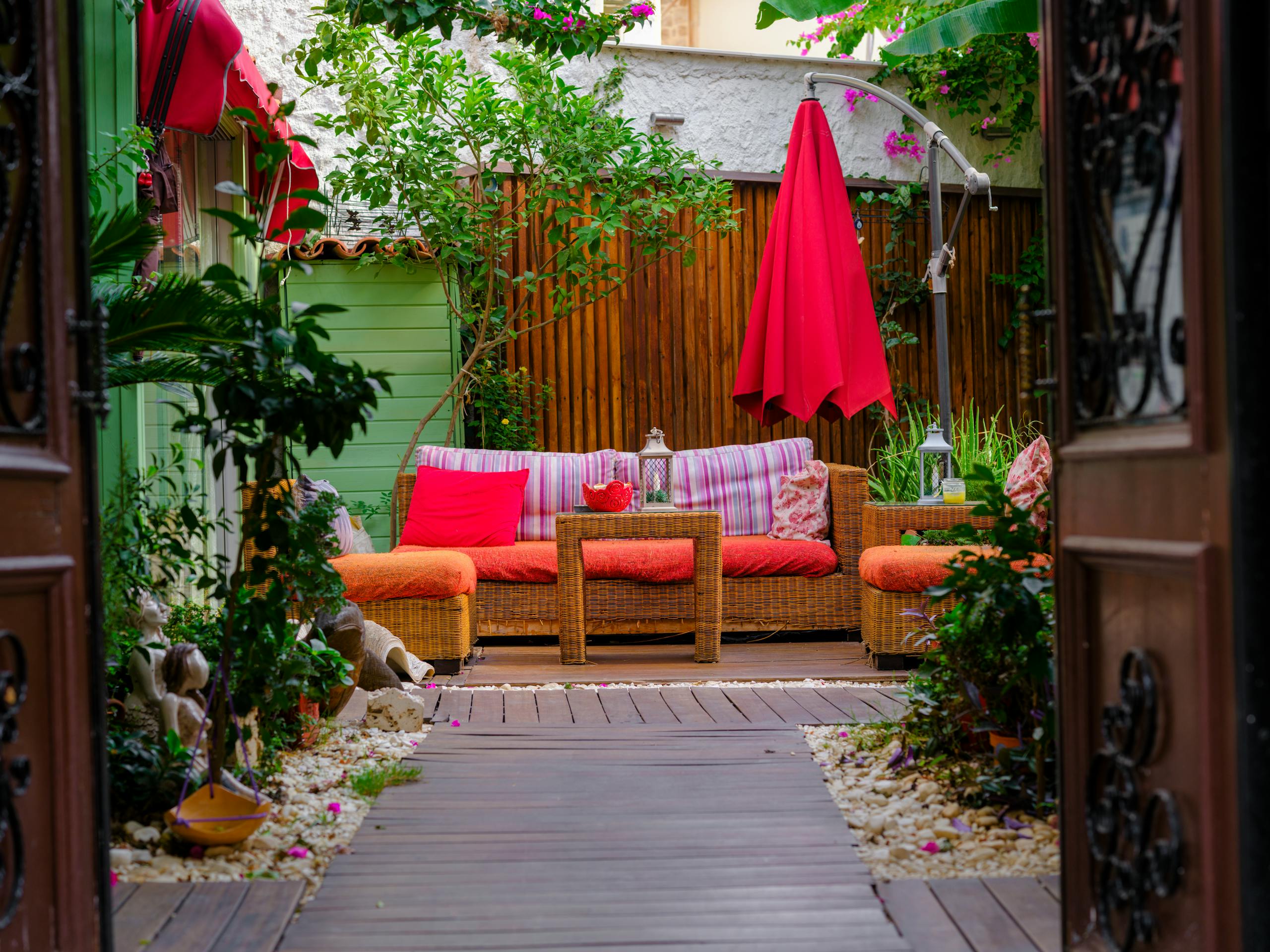 Vibrant outdoor patio with wicker furniture, bright cushions, and lush greenery for a cozy retreat.