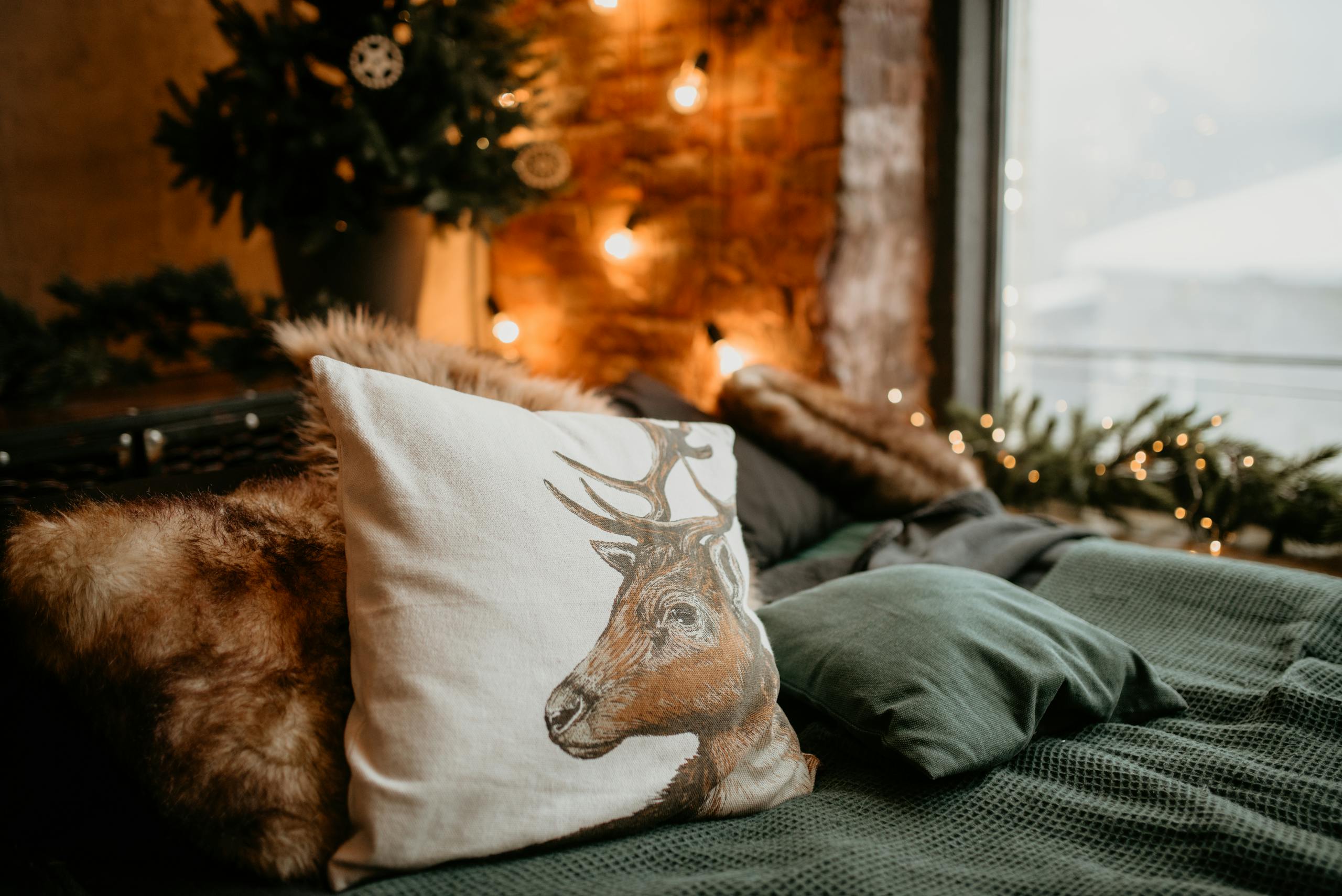 Warm and inviting bedroom featuring Seasonal festive decor and a deer pillow on a bed.Seasonal bedroom accessories with chunky knit throw and velvet cushions for an organised bedroom holiday retreat