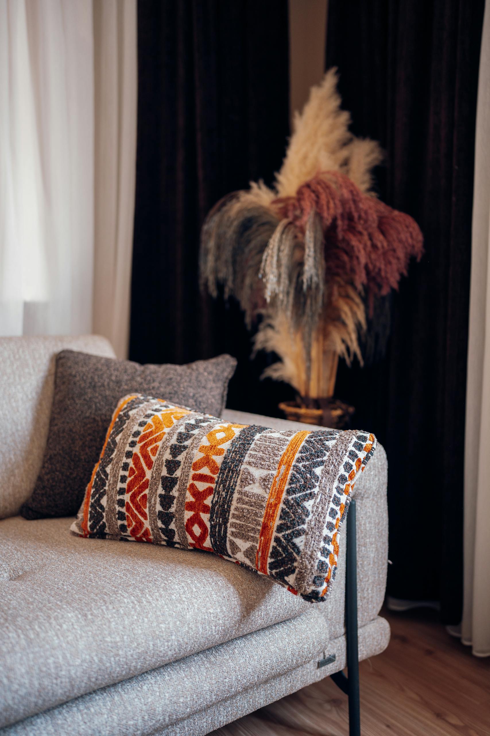 Afrohemian decor pieces layered textiles and mudcloth cushions on a neutral sofa