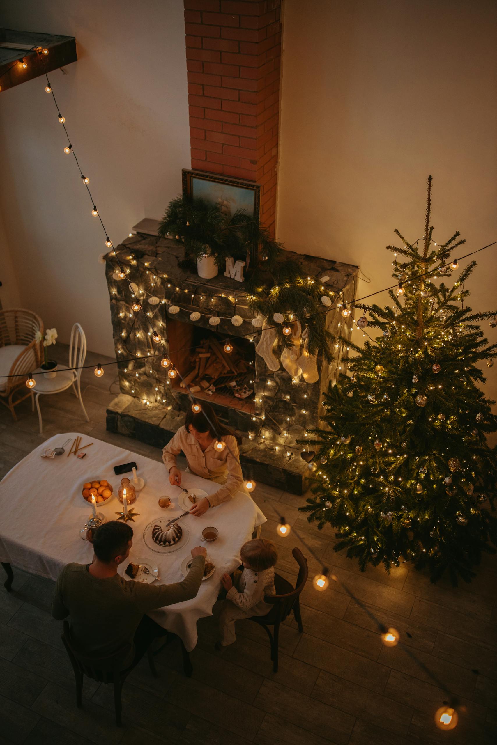 Warm family gathering around festive dinner table with Christmas tree and decorations.