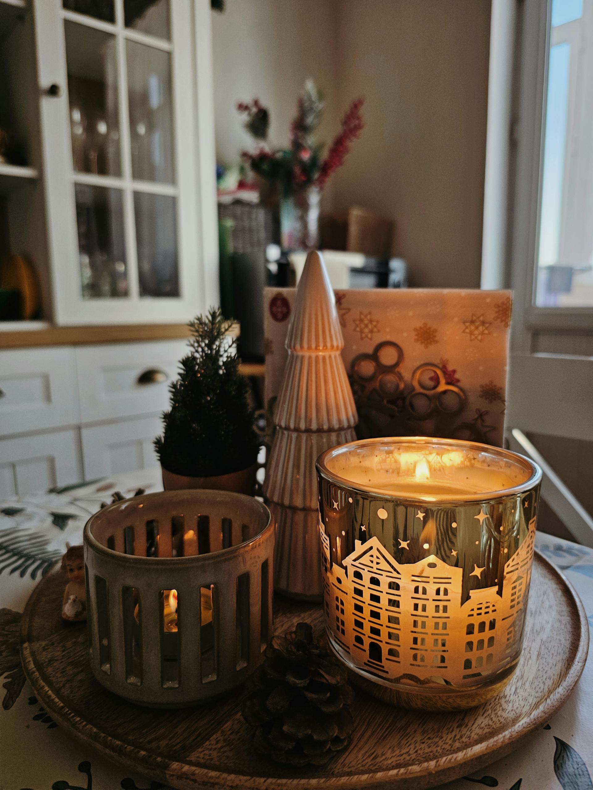 Warm, festive ambiance with lit candles and a small Christmas tree indoors.