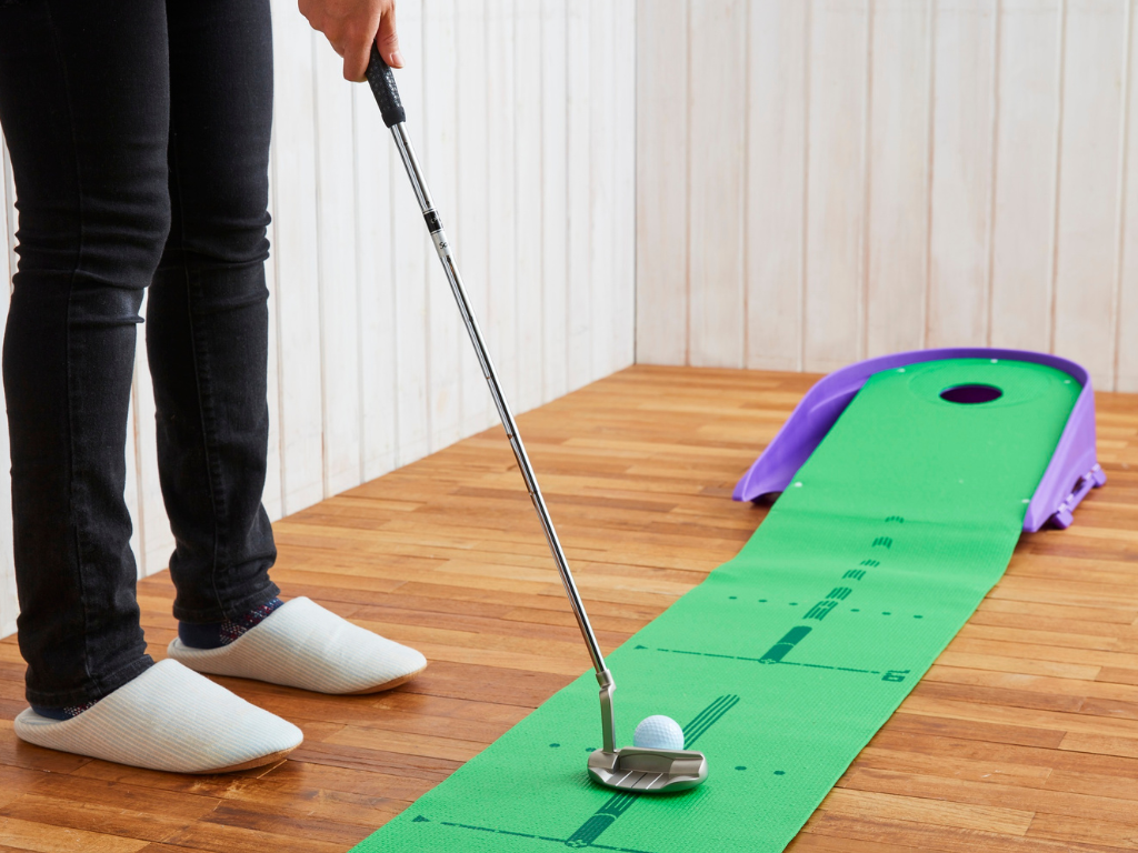 Man potting a golf ball on an Indoor Roll out putting green with hole,