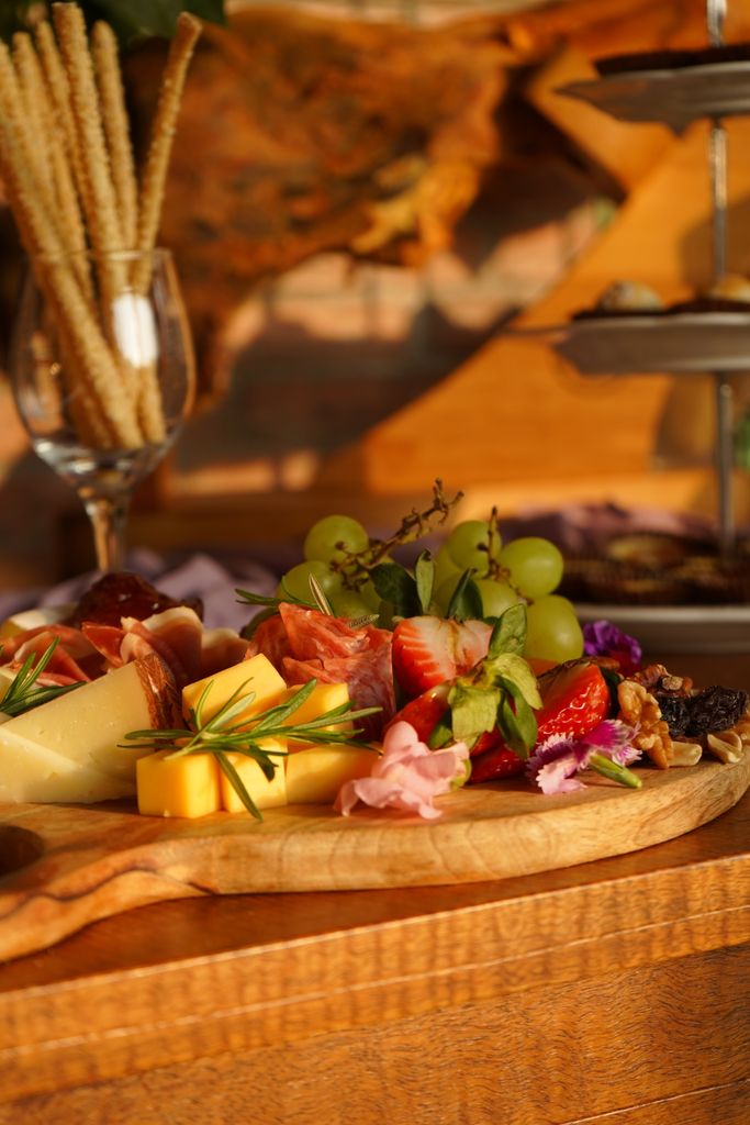 A rustic Gorgeous Grazing board featuring cheeses, fresh fruits, nuts, and cured meats on a wooden table.
