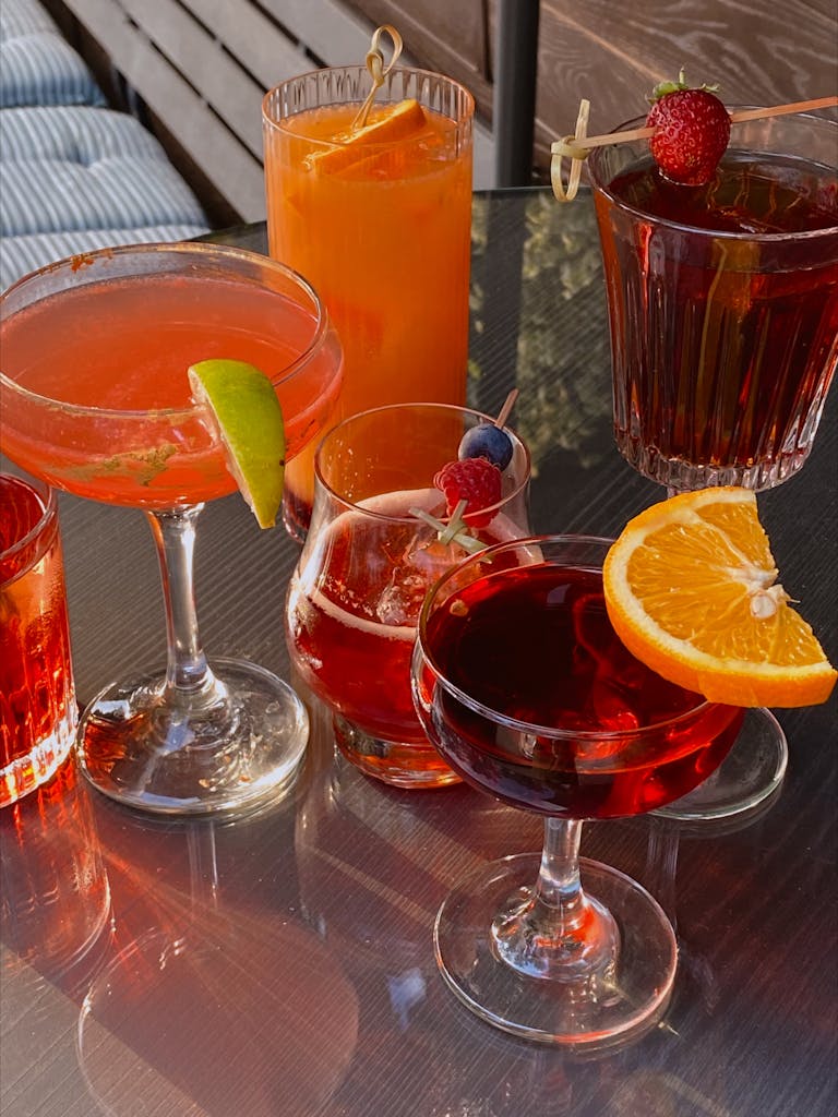 A variety of colorful cocktails served in different glasses on an outdoor table.