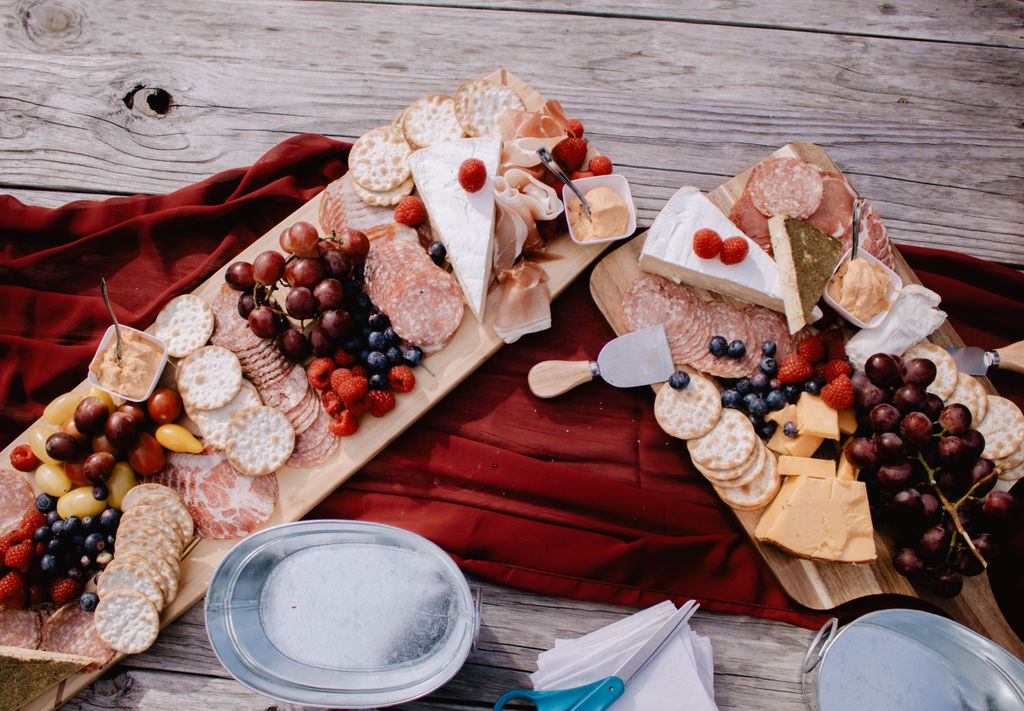 Aerial view of a Grazing board with cheeses, meats, fruits, and crackers on a wooden table.