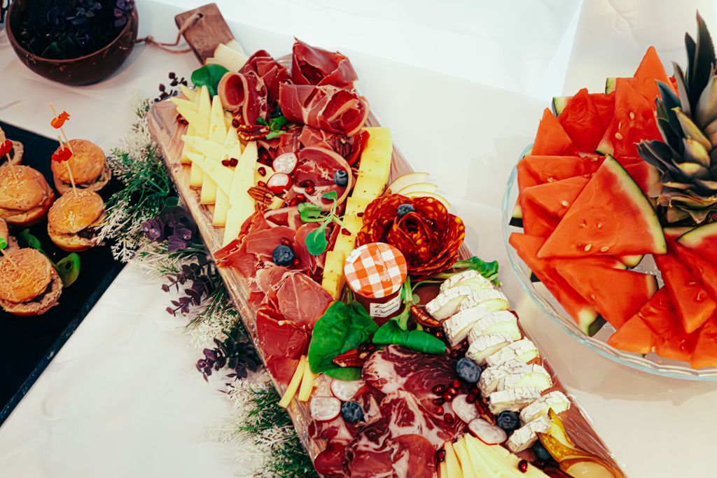 A Gorgeous Grazing table board featuring meats, cheeses, and fresh fruit slices for a gourmet summer snack.