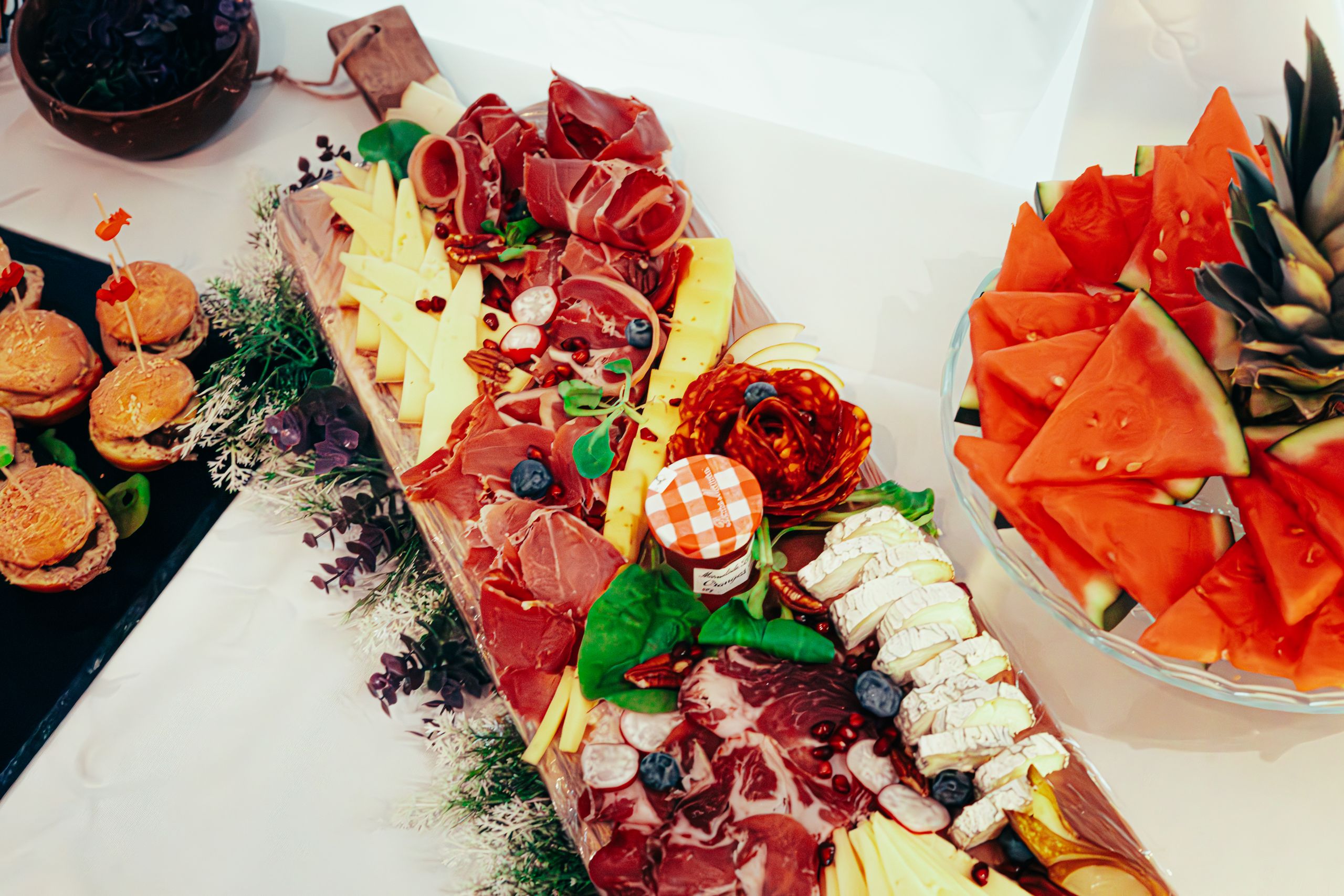 A Gorgeous Grazing table board featuring meats, cheeses, and fresh fruit slices for a gourmet summer snack.