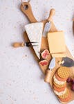 Delicious charcuterie board featuring cheeses, crackers, and figs and cheese knives on a wooden board.