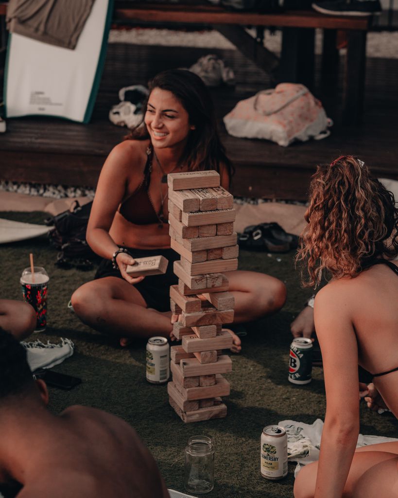 Group of friends playing Giant Jenga in the garden with outdoors, having fun during a summer staycation at home