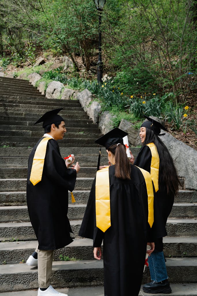 Group of graduates in gowns climbing outdoor steps, celebrating their achievement.
