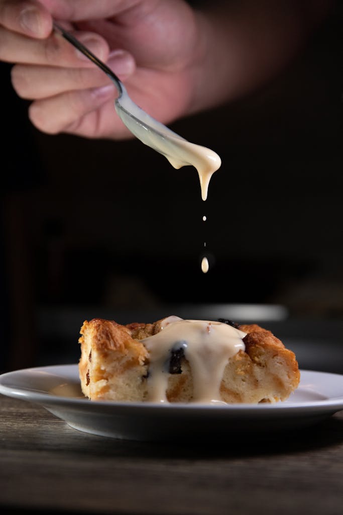 Indulgent homemade bread pudding topped with creamy vanilla sauce, captured in a stylish food. Pudding said in Britain means Dessert in America