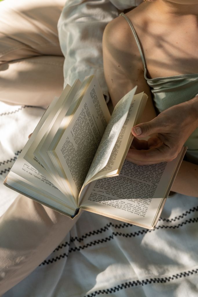 Person flipping through a book while lounging in a sunlit room, evoking relaxation i a summers reading nook