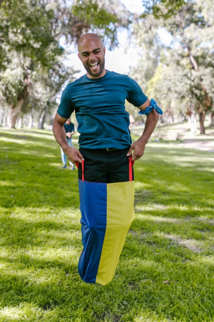 Smiling man participates in a vibrant sack race outdoors, showcasing team spirit.
