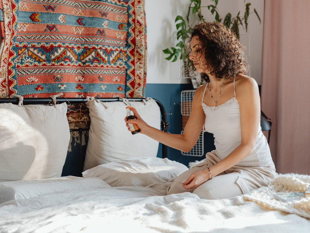 Woman spraying her bedroom pillows with a relaxing lavender pillow mist