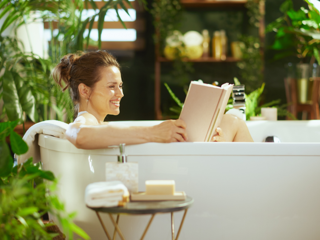 Woman relaxing in A Bath reading a book in summer on — at-home glow-up ideas for summer