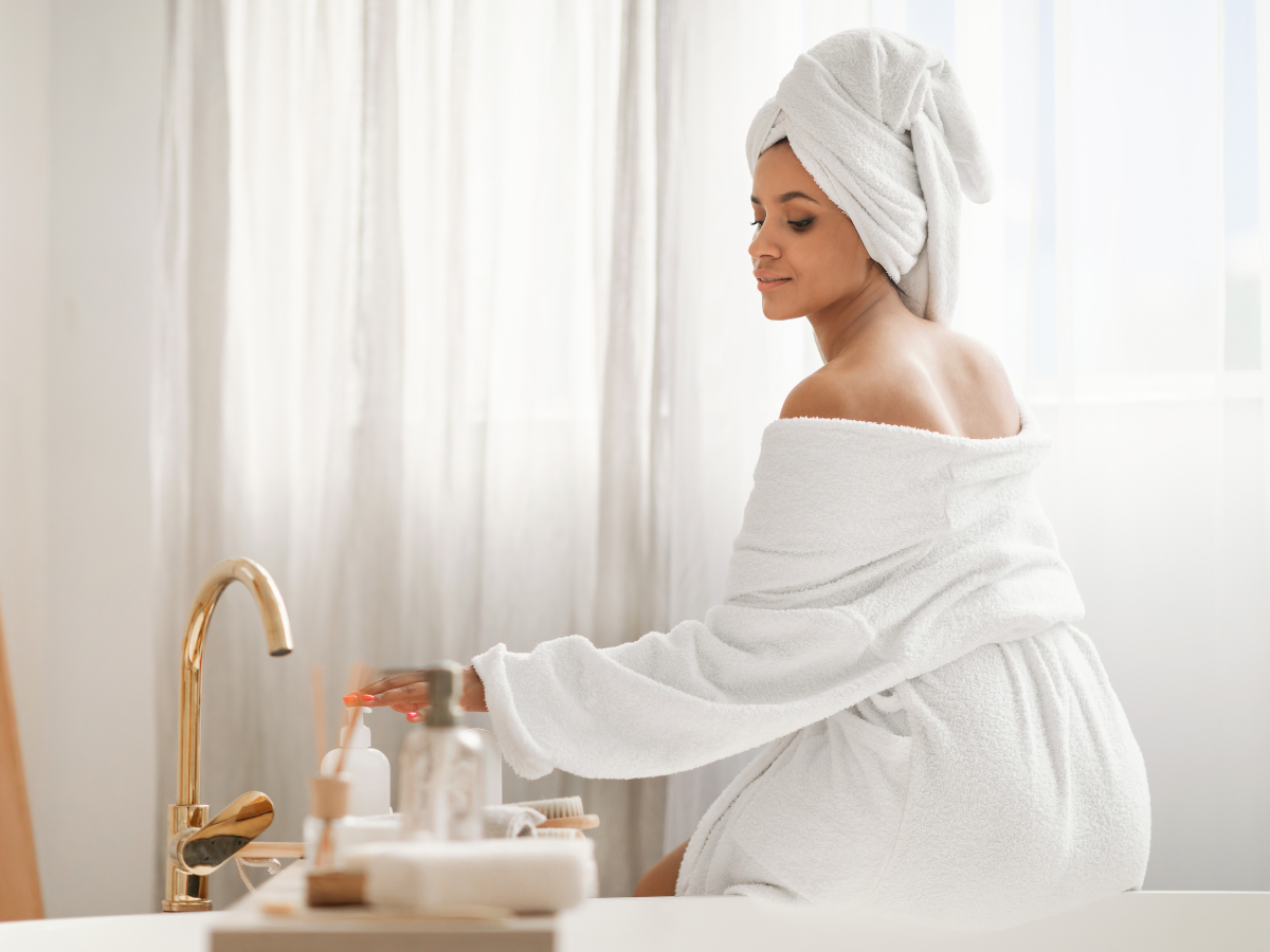 woman in a white bathrobe sat on a bath in a lovely bathroom for that hotel style feel
