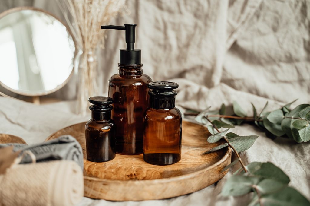 Stylish amber glass bottles on a rustic wooden tray, adding a cozy Hotel style bathroom.