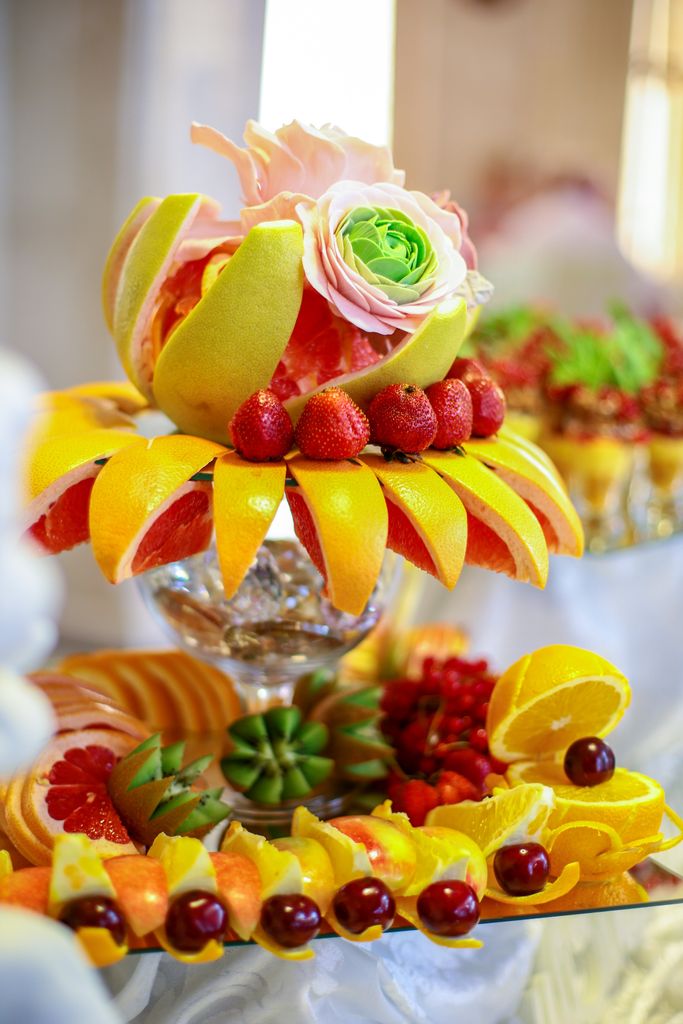 Vibrant display of freshly sliced fruits and decorative gorgeous grazing table with flowers on an elegant table setting.