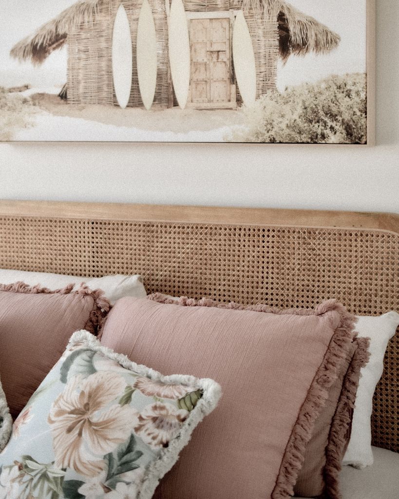 Beach-inspired interior bedroom with woven rattan headboard behind made up bed.
