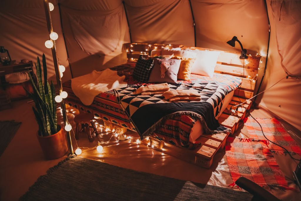 Cozy bed set up inside a bell tent for backyard camping comfort]