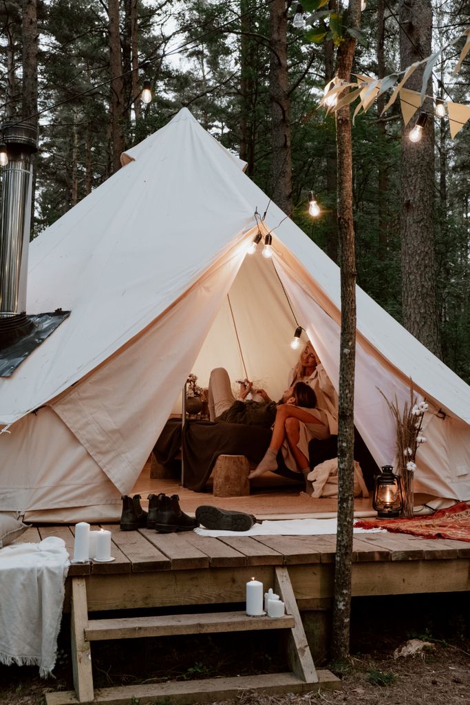 Spacious bell tent interior set up for a garden glamping staycation with fairy lights and cushions