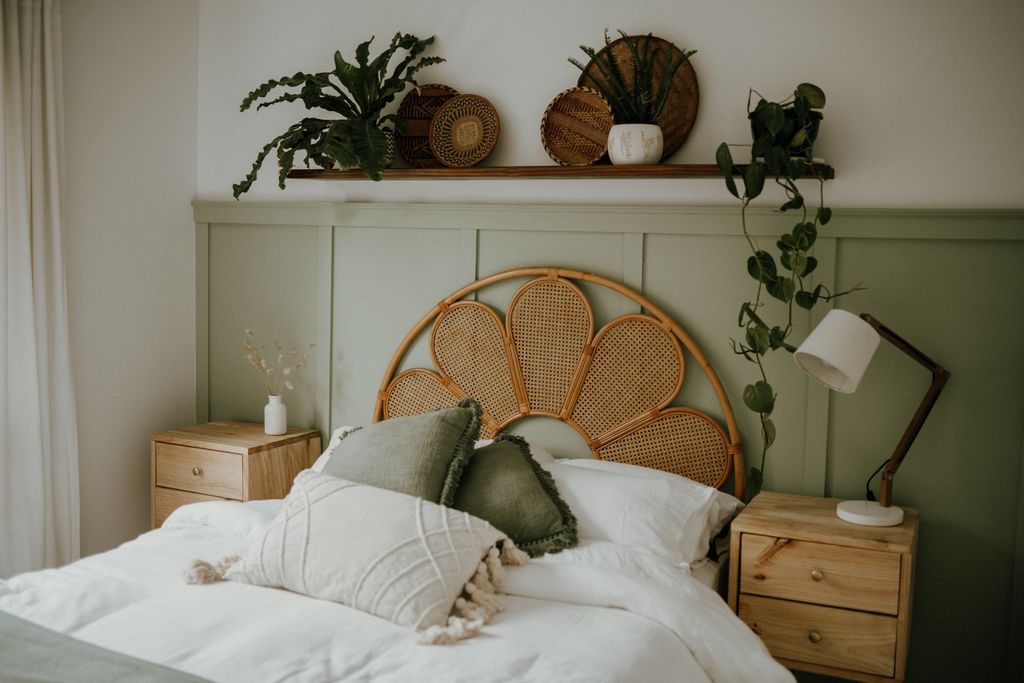 A warm Scandinavian bedroom featuring natural wicker decor and lush green plants.