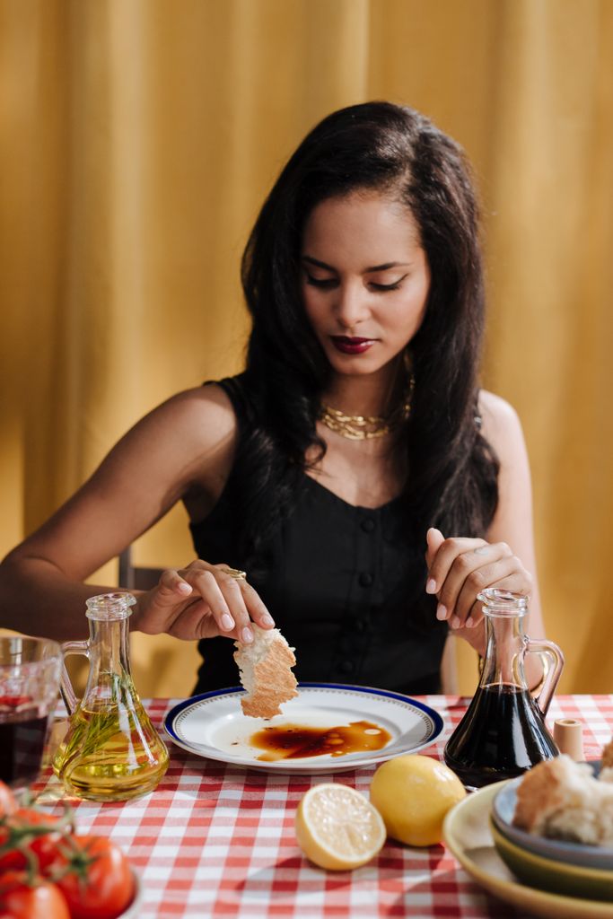 Woman eating bread with ceramic oil and vinegar bottles