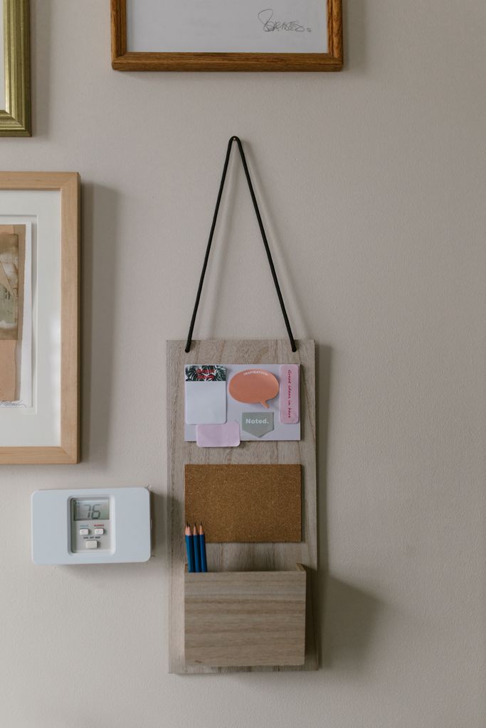 Hanging wooden wall organizer with cork board and pencils for efficient home storage.