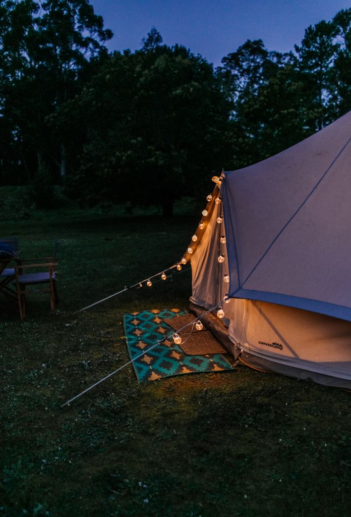 Solar festoon lights strung along entrance of bell tent for evening glamping ambience