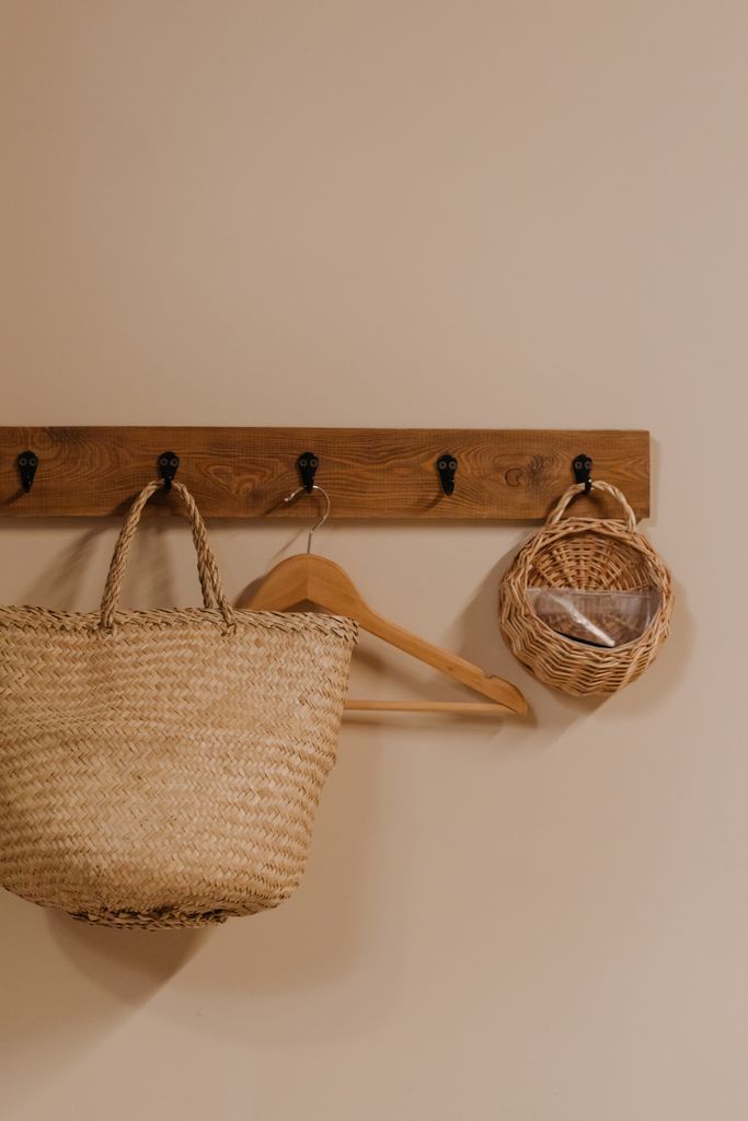 Minimalist interior displaying a woven storage basket and wooden hanger on a rack for natural home decor.