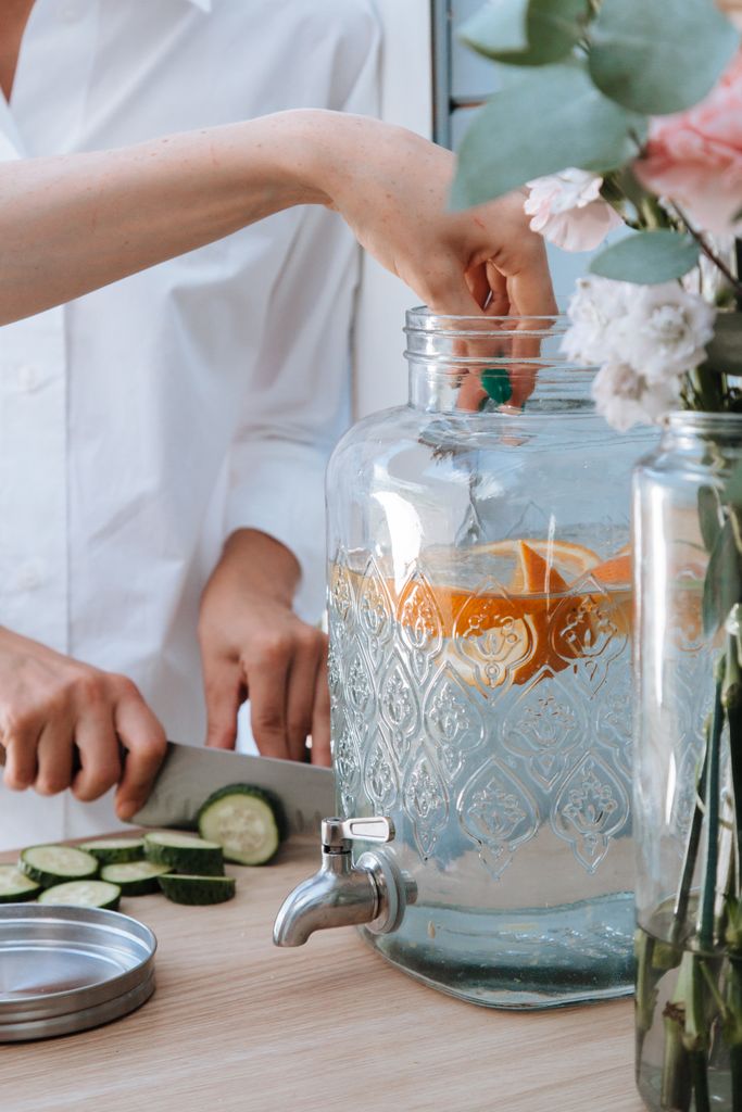 glass drinks dispenser on kitchen counter filled with citrus infused water.