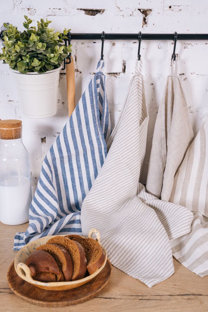 Rustic Kitchen scene Featuring striped linen tea towles hanging on black rail as part of amazon finds under £25 next to plate sliced bread