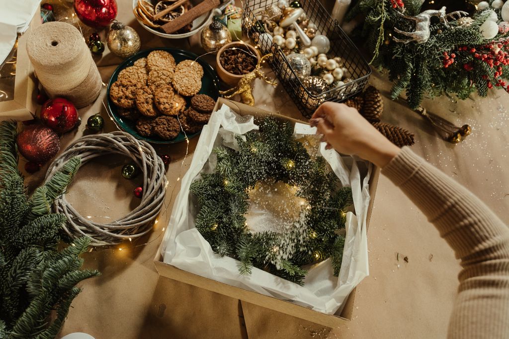 A cozy holiday scene with a Christmas wreath being decorated amidst festive ornaments and cookies.