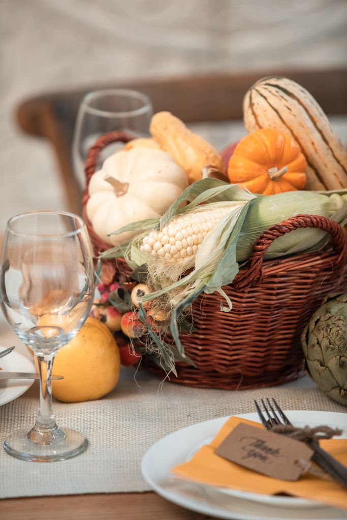 A traditional Thanksgiving still life with vegetables and wine glasses on a table.