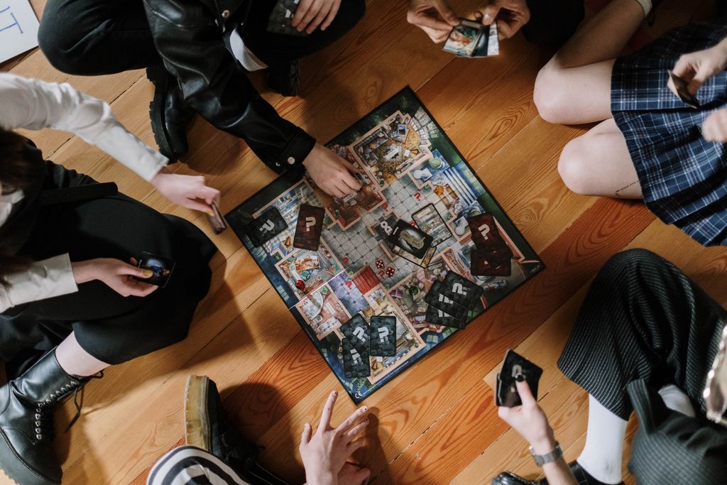 Aerial view of friends enjoying a board game on wooden floor.