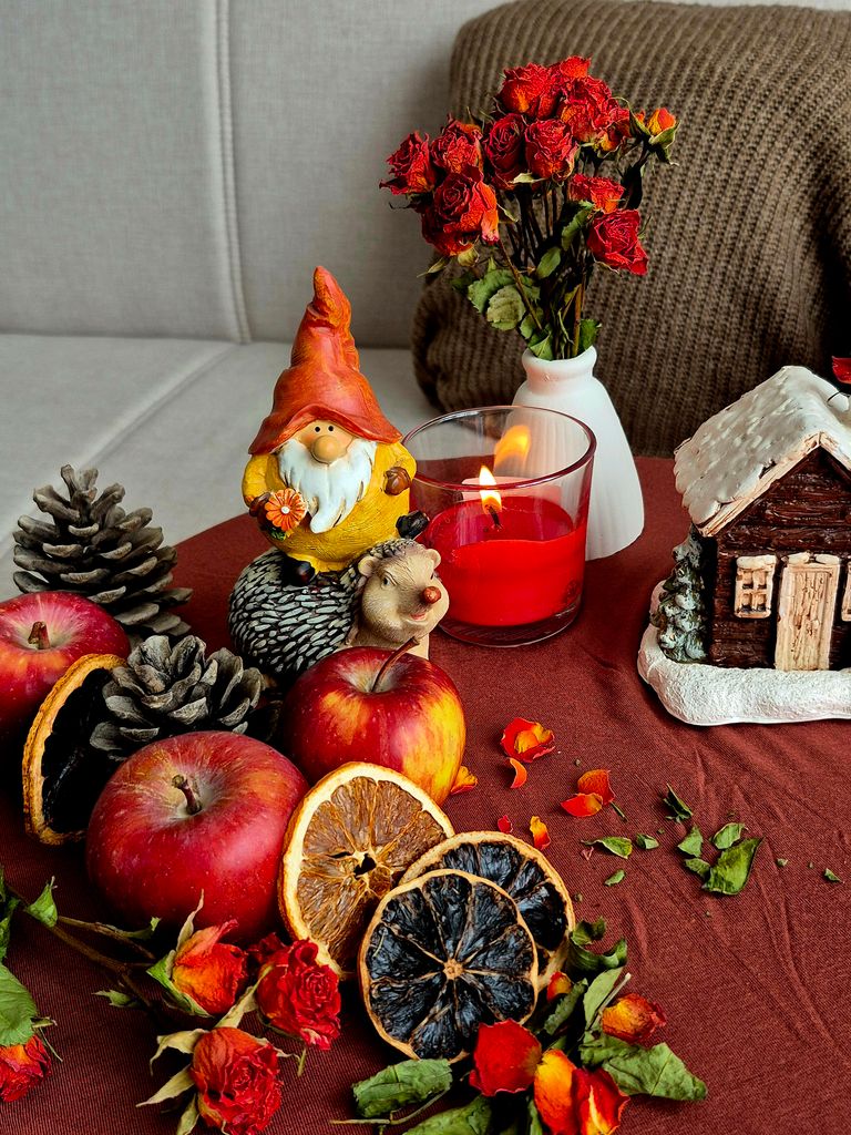 Autumn to Christmas decor themed still life with dried fruits, pinecones, and a decorative gnome on a table.