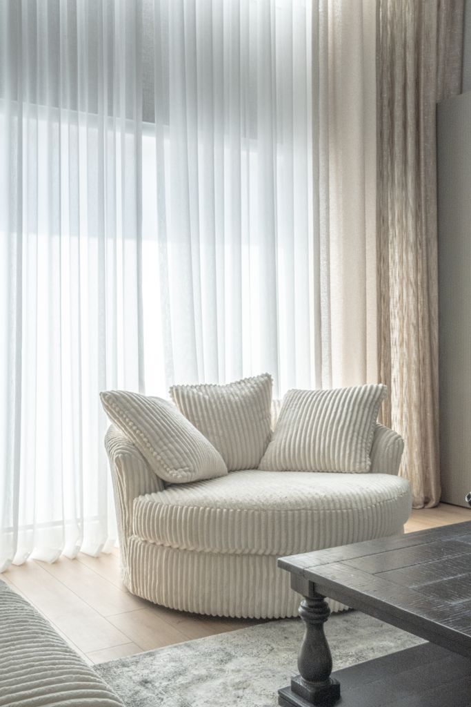 Bright living room with a round comfy chair and sheer curtains.