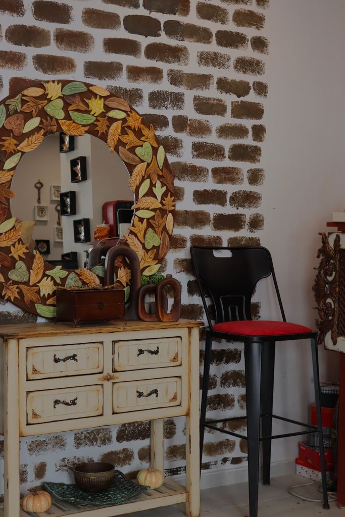 Cozy autumn-themed interior with a leafy mirror and rustic furniture against a brick wall.