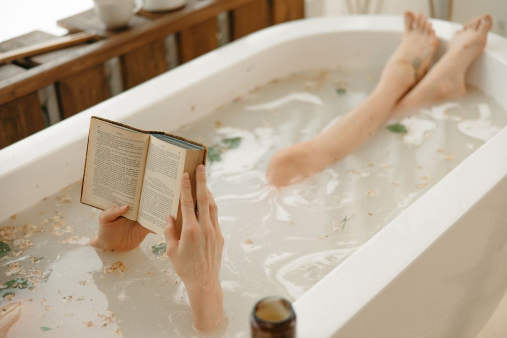 Cozy indoor scene of a person reading in a bathtub surrounded by warm light, perfect for an autumn self care Sunday