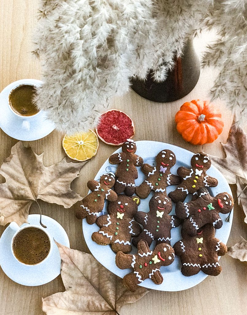 Decorative setup featuring gingerbread cookies, fall leaves, and hot drinks for a cozy autumn feel.