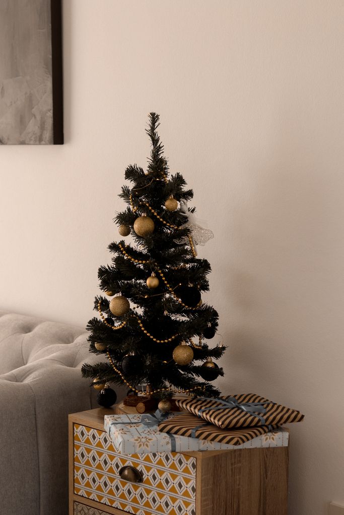 Elegant Christmas tree with decorations and gifts on a cabinet, perfect for holiday ambiance.