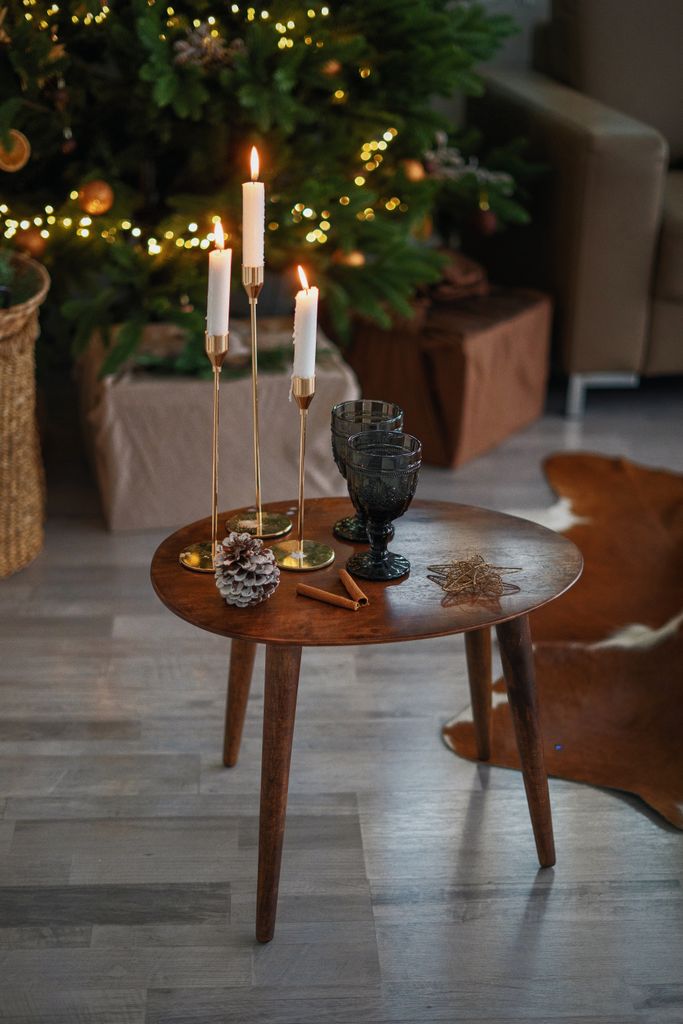 Festive Christmas decor with candles on a wooden table, set against a lit Christmas tree.