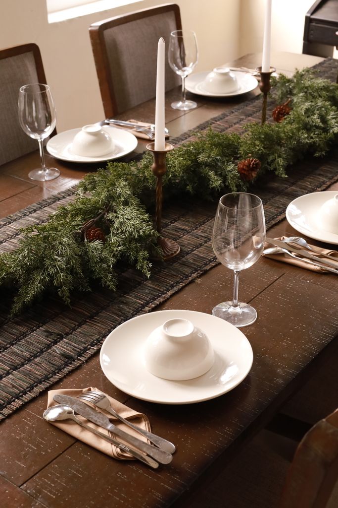 Festive table setup with greenery and candlesticks, perfect for holiday dinners.