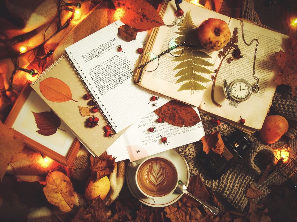 Flat lay of coffee, books, and autumn leaves creating a cozy fall atmosphere.