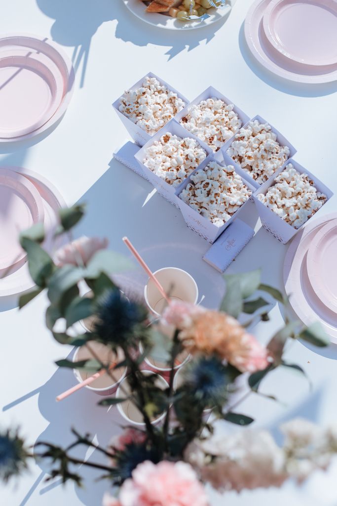 Overhead view of popcorn boxes with a pastel dining setup and floral decoration.
