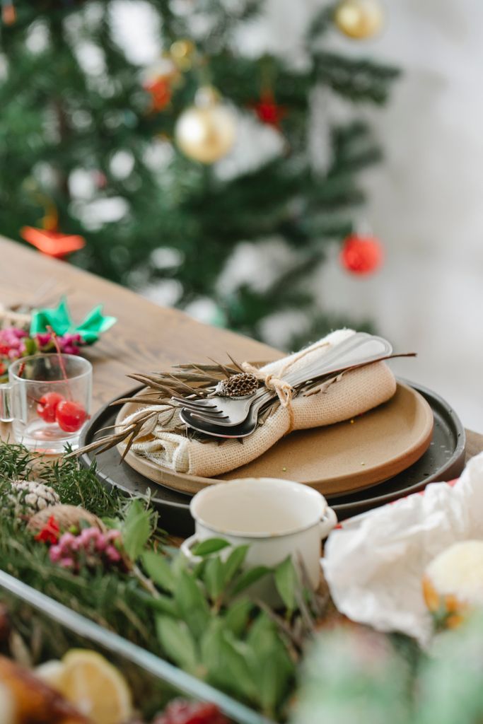 Served table with dishware and cutlery near fir sprigs during Christmas holiday in house